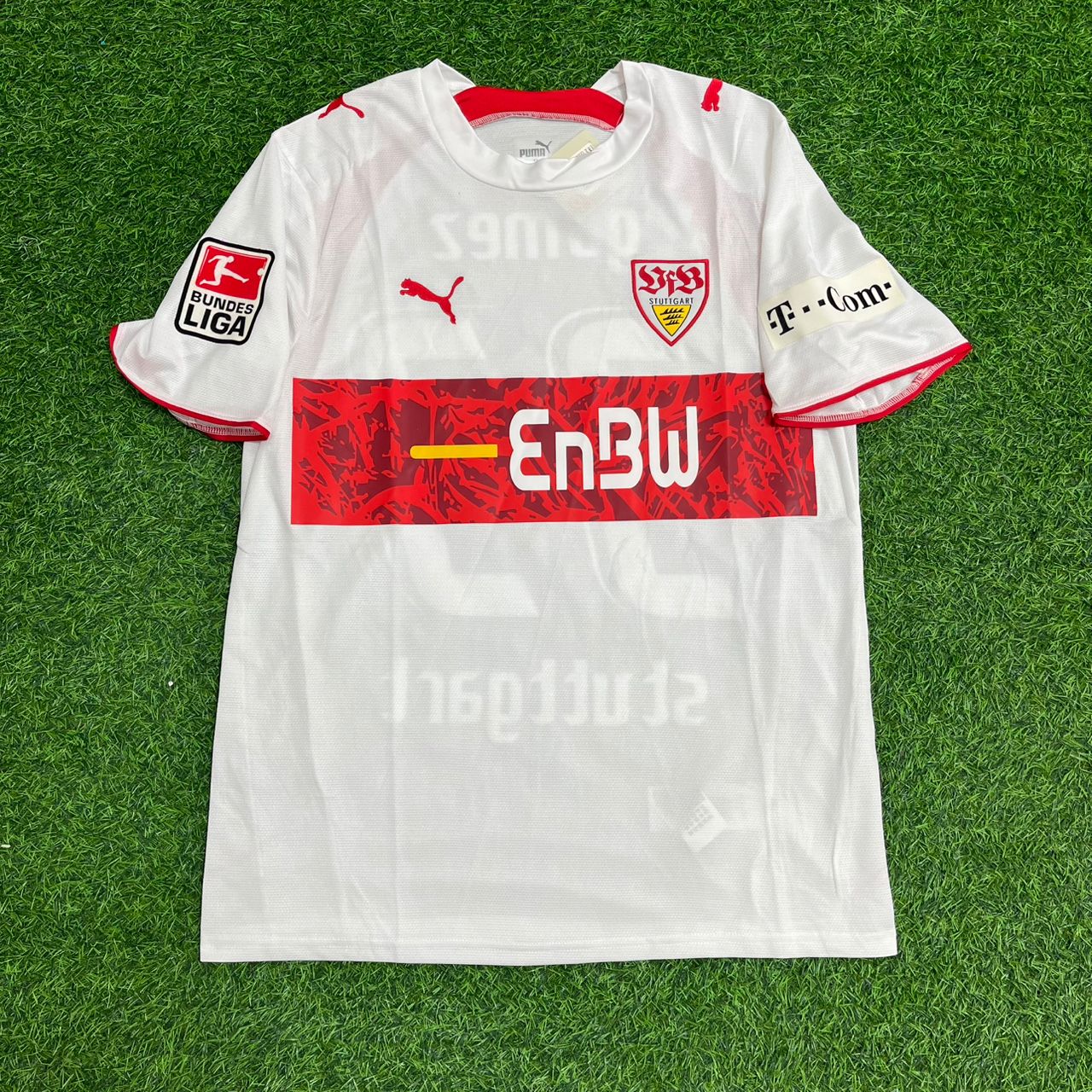White sports jersey with red and black details on a green grass background – Jersey Paradise Edition